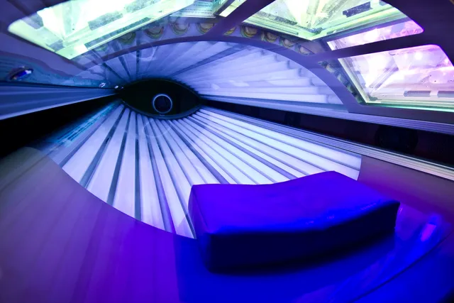 Interior of a modern tanning bed with blue and purple lighting.