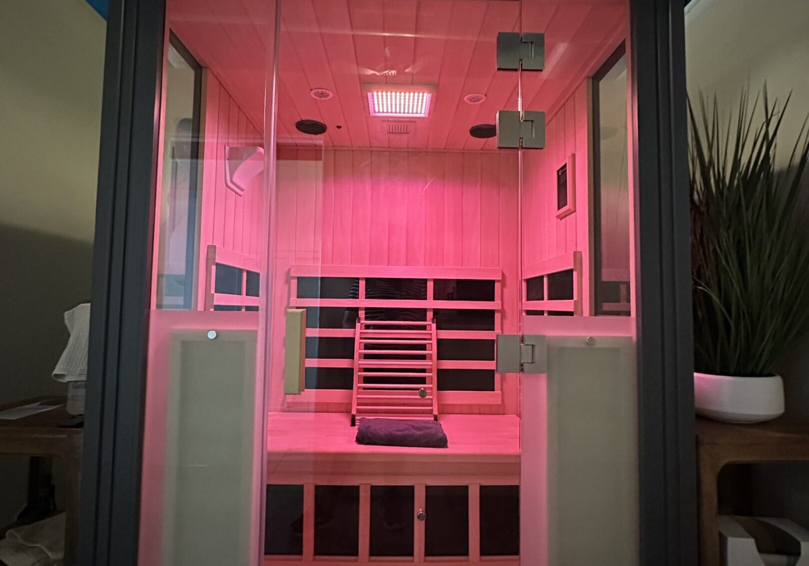 Modern infrared sauna cabin glowing with red light inside a home.